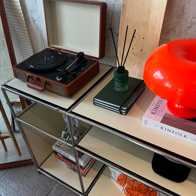 A turntable, notebooks and an orange mushroom lamp on a shelf